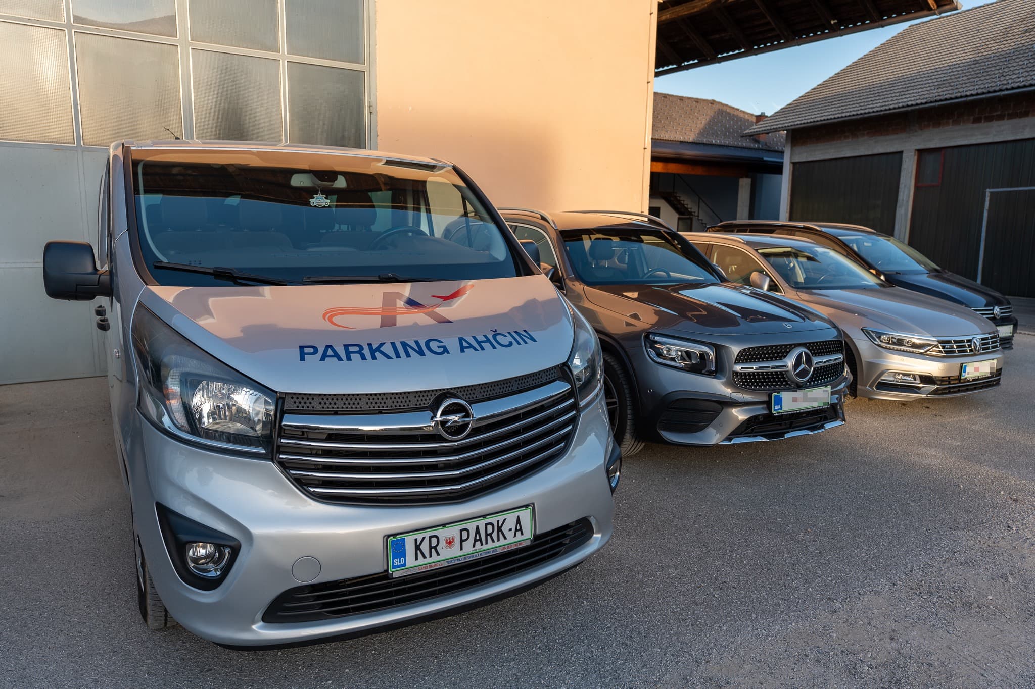 Avtomobili strank na odprtem parkirišču, spredaj kombi Parking Ahčin